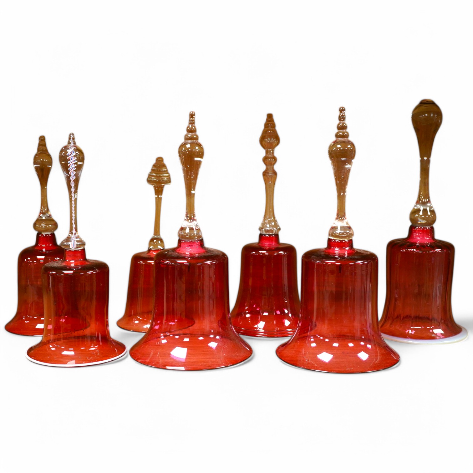 Seven Victorian cranberry glass bells, one with patriotic opaque twist handle, largest 30cm high. Condition - fair/good